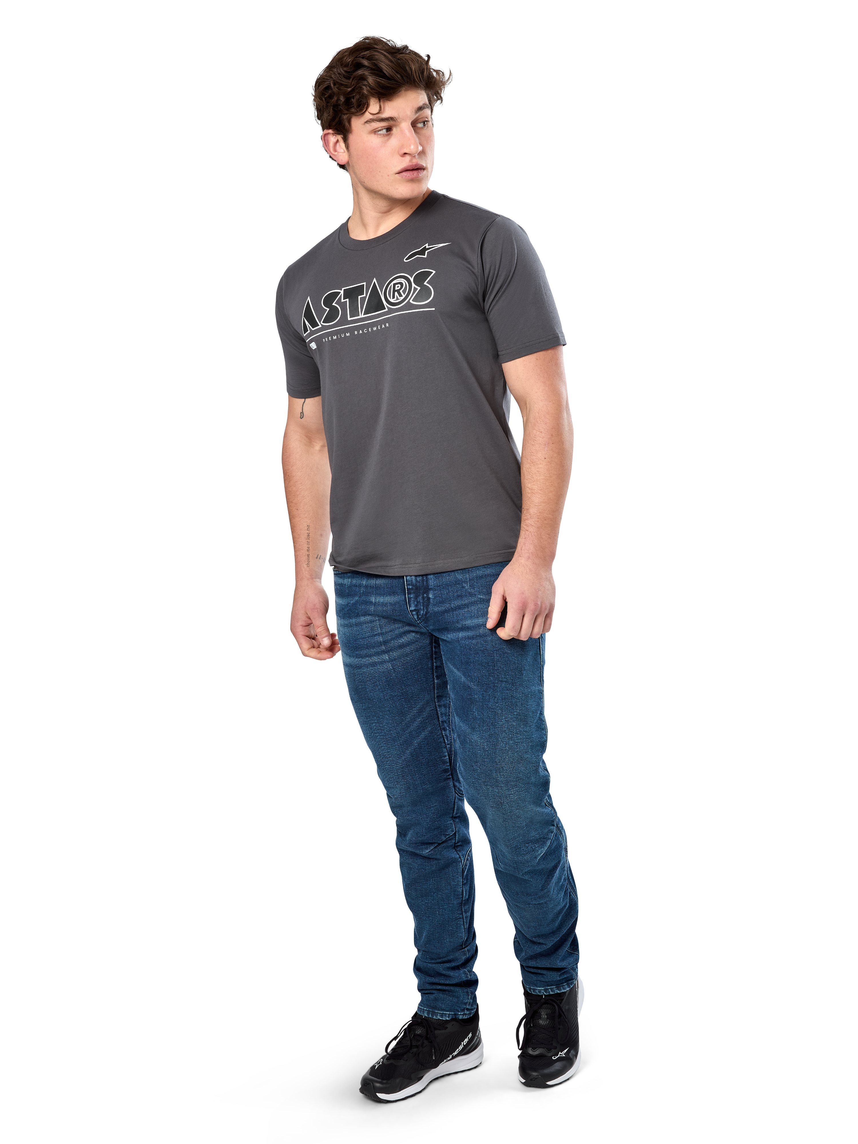 Alpinestars Cereal CSF Tee, Kurzarm-T-Shirt, Anthrazit, weißes geometrisches Astars-Textlogo, lässige Motorsport-Streetwear, kombiniert mit blauen Jeans und schwarzen Sneakern