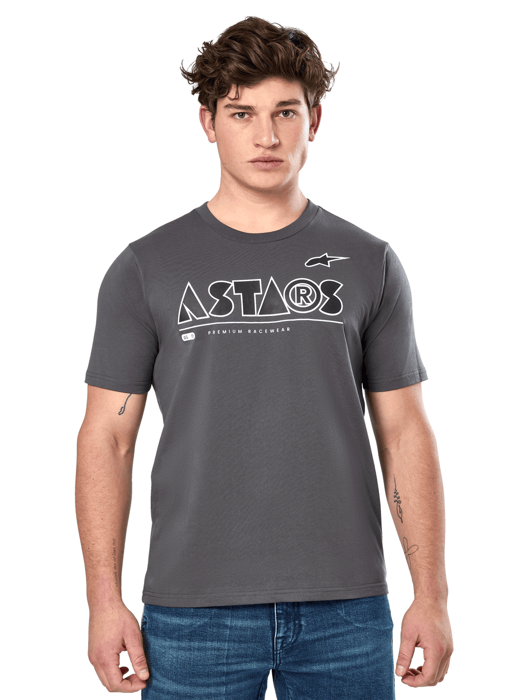 Alpinestars Cereal CSF Tee, anthrazitgraues Kurzarm-T-Shirt, getragen von einem männlichen Model mit blauen Jeans, weißes geometrisches ASTARS-Logo und „Premium Racewear“-Schriftzug, lässige motorsport-inspirierte Lifestyle-Bekleidung
