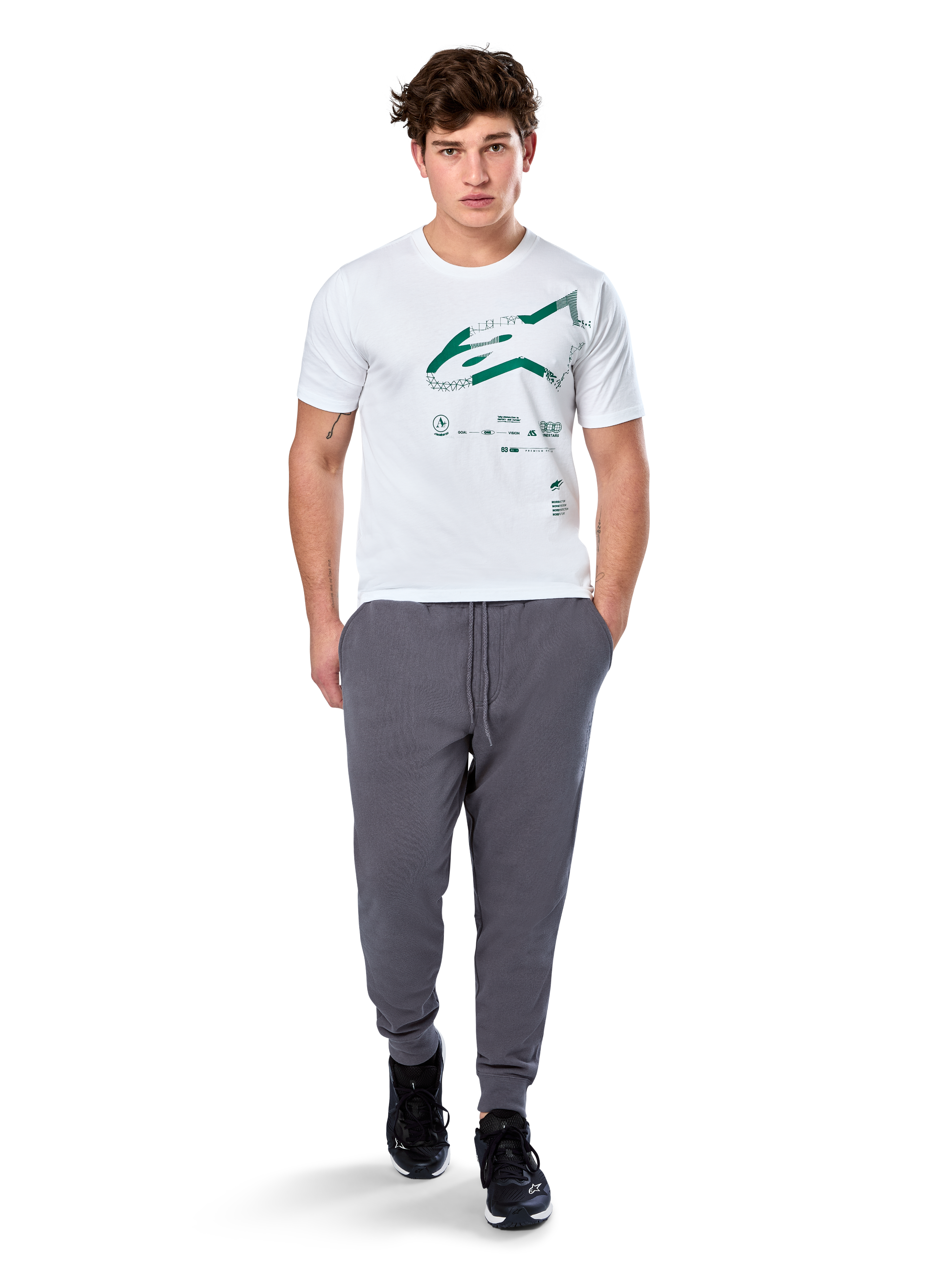 Alpinestars Geografica CSF Tee, Kurzarm-T-Shirt, Weiß, grünes Astars-Logo mit geografischer Multi-Tech-Grafik, getragen mit grauer Jogginghose und schwarzen Sneakern, lässige Motorsport-Streetwear