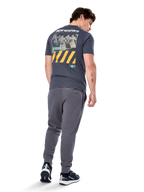 Alpinestars No Barrier CSF Tee, kurzärmeliges T-Shirt, Anthrazit, Rückansicht mit großer Distressed-Fotografik, gelben diagonalen Streifen und weißem Logo, lässige, vom Motorsport inspirierte Streetwear