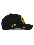 Alpinestars Luminary Cap, schwarze Snapback-Mütze, Seitenansicht, gebogener Schirm mit gelbem Sutache-Besatz, gelbes 3D-Sticklogo und Stern an der Seite, 100 % Baumwoll-Twill, lässige Motorsport-Kopfbedeckung
