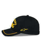 Alpinestars Luminary Cap, schwarze Snapback-Mütze in der Seitenansicht, gelbe 3D-Stickerei auf der Vorderseite und an der Seite, gebogener Schirm mit gelbem Sutache-Besatz, strukturierte Baumwoll-Twill-Konstruktion