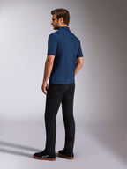 Alpinestars Impetus Sport Polo, kurzärmeliges Poloshirt in Marineblau, Rück- und Seitenansicht am Model, kombiniert mit schwarzer Hose und schwarzen Sneakern, lässige Motorsport-Lifestyle-Sportbekleidung