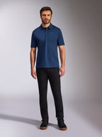 Alpinestars Impetus Sport Polo, Kurzarm-Poloshirt, Marineblau, kleines silbernes Astars-Logo auf der Brust, Drei-Knopf-Leiste, getragen von einem Modell mit schwarzer Hose und Stiefeln, lässige vom Motorsport inspirierte Sportbekleidung