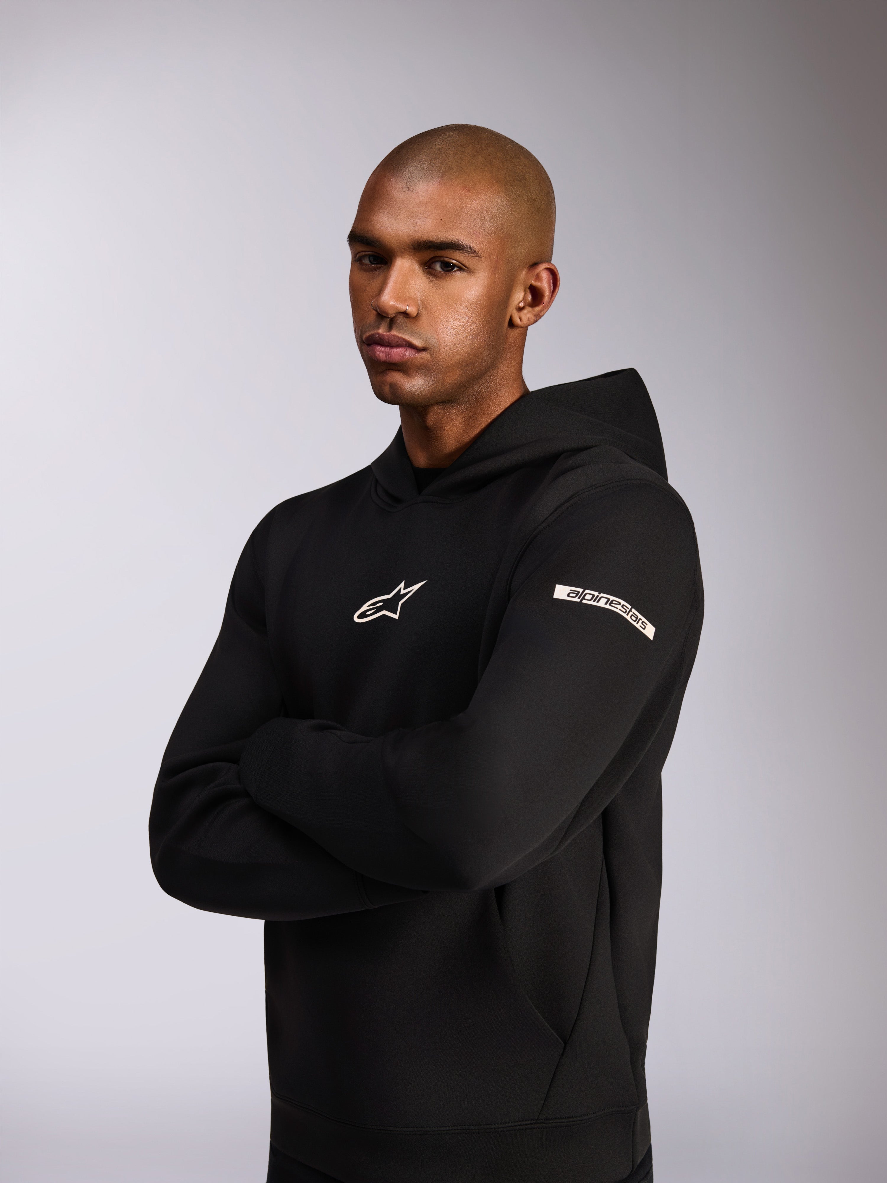 Alpinestars Insight Hoodie, casual sportswear hoodie, Black, white Astars logo on chest and word logo on the upper sleeve, model wearing hoodie with arms crossed, premium double face fleece construction