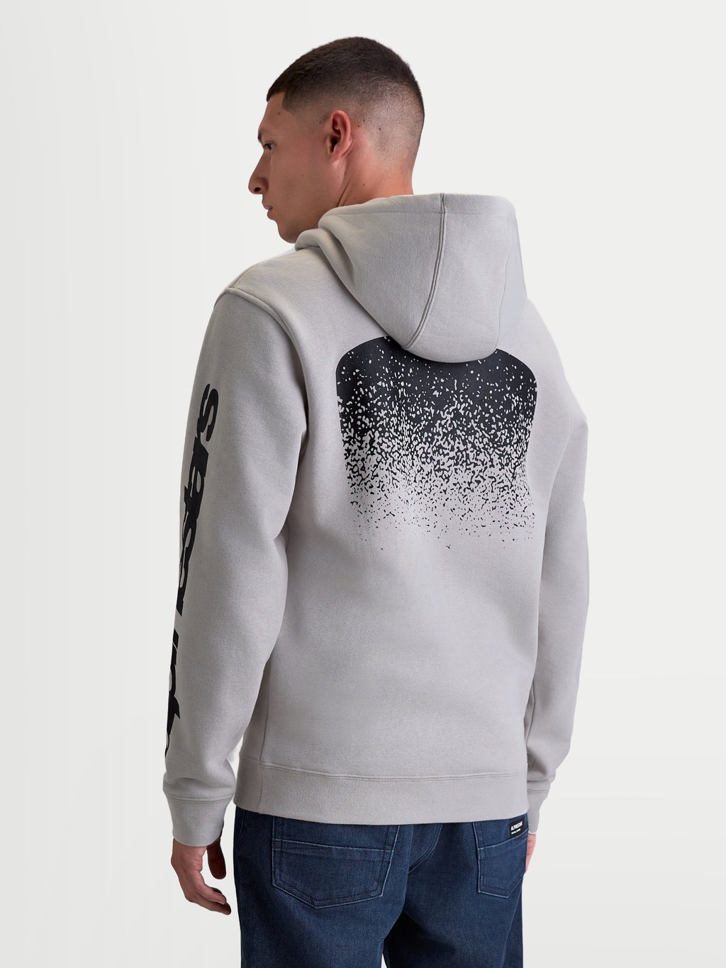 Alpinestars Obsessed Hoodie, Herren-Sportswear-Kapuzenpullover in Grau, Rückansicht am Modell, große schwarze MX-Grafik mit Farbverlauf auf dem Rücken und Alpinestars-Branding am Ärmel, lässige Motorsport-Lifestyle-Bekleidung aus Fleece.