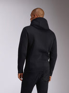 Alpinestars Ellipsoid Hoodie, Schwarz, Rückansicht einer Person, die einen Fleece-Kapuzenpullover trägt, lange Ärmel mit Rippbündchen an Ärmeln und Saum, kombiniert mit schwarzen Jeans, lässige Motorsport-inspirierte Sportbekleidung