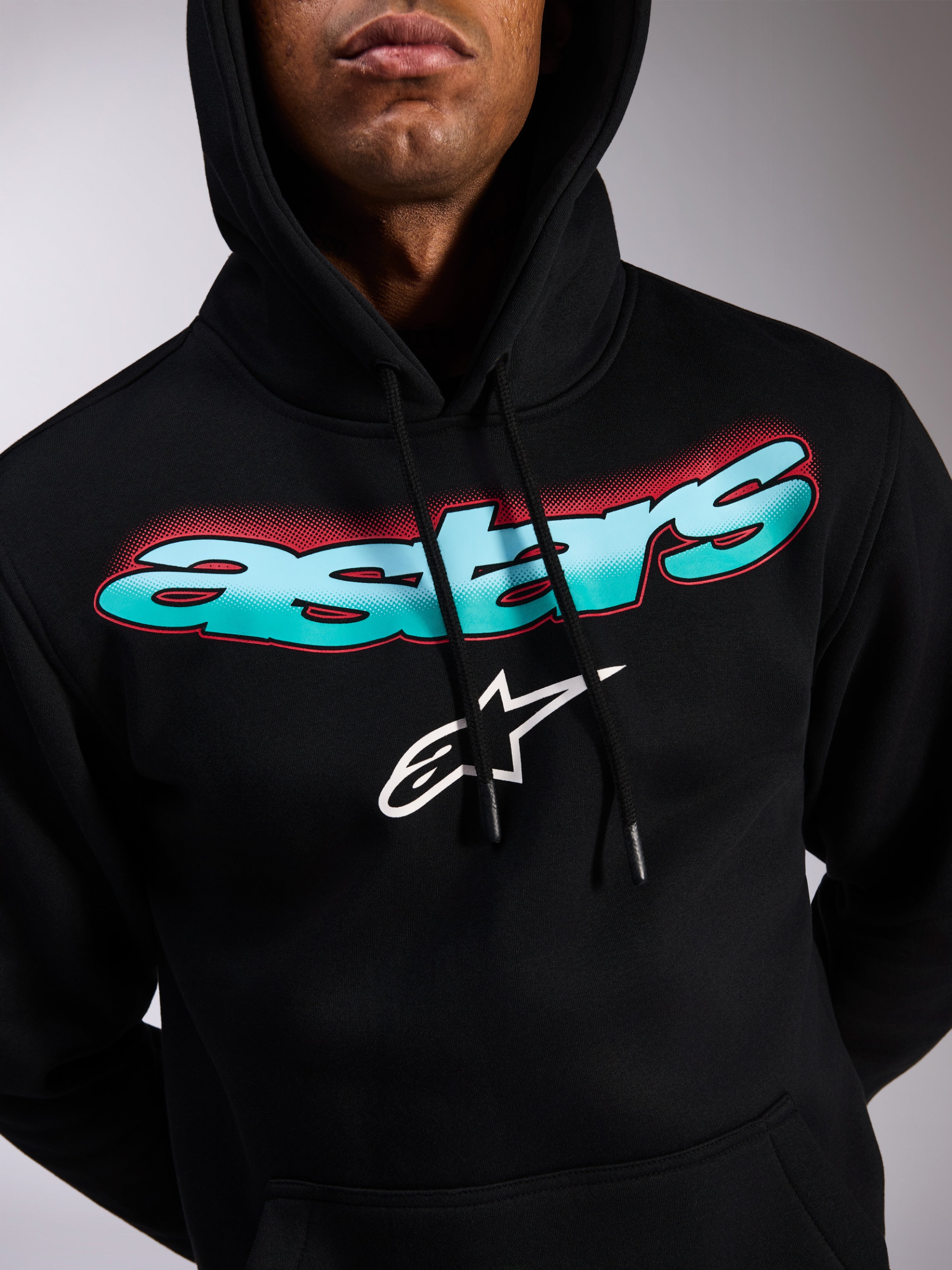 Alpinestars Ellipsoid Hoodie, schwarzer Fleece-Kapuzenpullover, Astars-Schriftzug mit blau-türkisem Farbverlauf und roten Halbtoneffekten, weißes Stern-Logo, Kapuze mit Kordelzug, lässige, vom Motorsport inspirierte Streetwear
