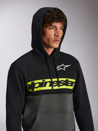Alpinestars Parallel Hoodie, lässige Streetwear im Color-Block-Design, oben Schwarz und unten Gunmetal-Grau, neongelber Bruststreifen mit schwarzem Alpinestars-Wortlogo, weißes Astars-Logo, Kapuzenpullover mit Kordelzug