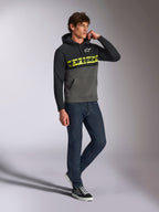 Alpinestars Parallel Hoodie, lässige Streetwear, Color-Block-Design in Schwarz und Gunmetal-Grau, neongelber Alpinestars-Schriftzug auf der Brust, weißes Astars-Logo, Kapuze mit Kordelzug, getragen mit dunklen Jeans und Sneakern
