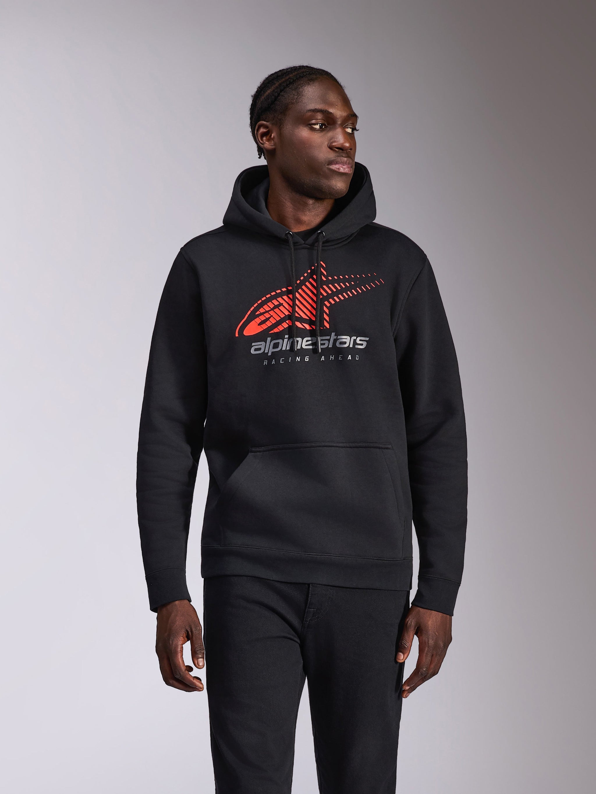 Alpinestars Pulse Hoodie, lässiger Kapuzenpullover, Schwarz mit rotem und grauem Astars-Logo mit Speed-Line-Fade und „Racing Ahead“-Schriftzug, Kapuze mit Kordelzug und Kängurutasche, Motorsport-inspirierte Streetwear, getragen von einem Model