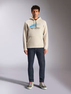 Alpinestars Pulse Hoodie, Off-White, Langarm-Kapuzenpullover mit Kordelzug, blau-schwarzes Astars Combo-Logo mit Speed-Line-Fade, kombiniert mit dunkler Jeans und Sneakern, lässige Motorsport-Streetwear
