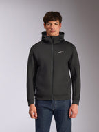 Alpinestars Cypher Hoodie, schwarzer Fleece-Hoodie mit Frontreißverschluss, Kapuze mit hohem Kragen und weißem Branding, kleines weißes Astars-Logo auf der Brust, getragen von einem Model mit blauen Jeans, lässige vom Motorsport inspirierte Streetwear.