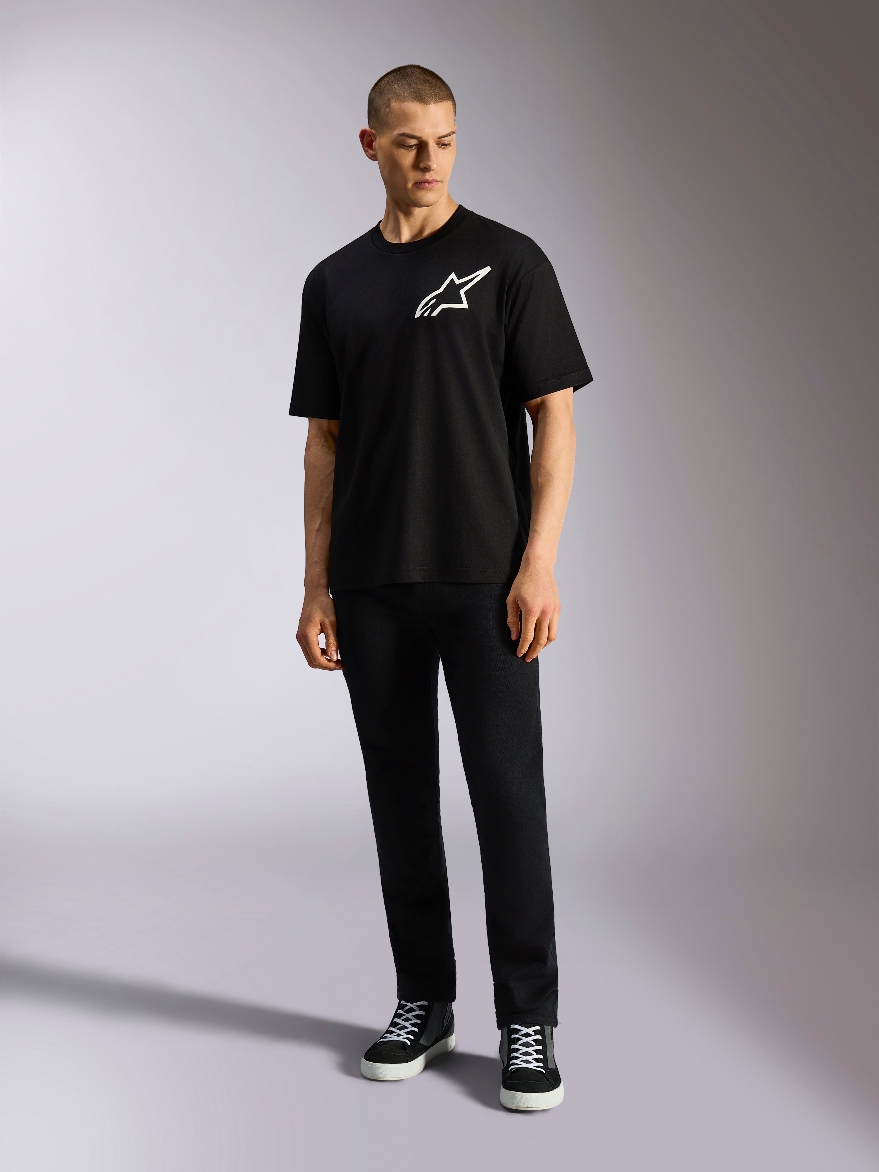 Alpinestars One Oversized CSF Tee, Kurzarm-T-Shirt, Schwarz, weißes Astars-Logo auf der Brust, Oversized-Passform, getragen von Model mit schwarzer Hose und Sneakern, lässige Lifestyle-Streetwear