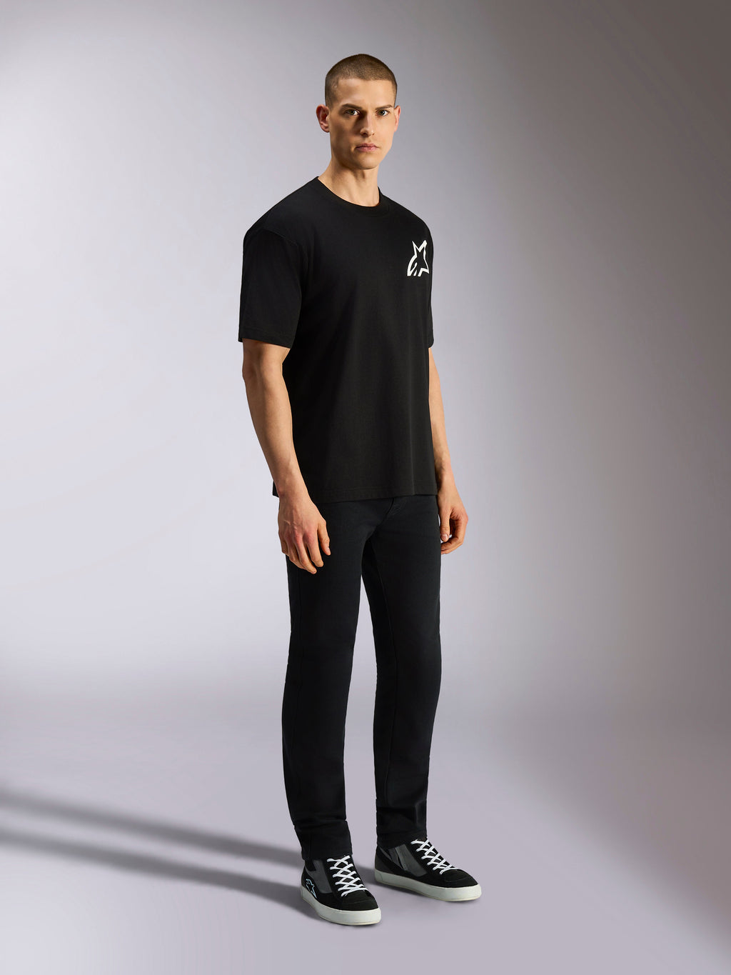 Alpinestars One Oversized CSF Tee, Kurzarm-T-Shirt, Schwarz, weißes Astars-Logo auf der Brust, Oversized-Passform, getragen von einem männlichen Model mit schwarzer Hose und Sneakern, lässige vom Motorsport inspirierte Streetwear