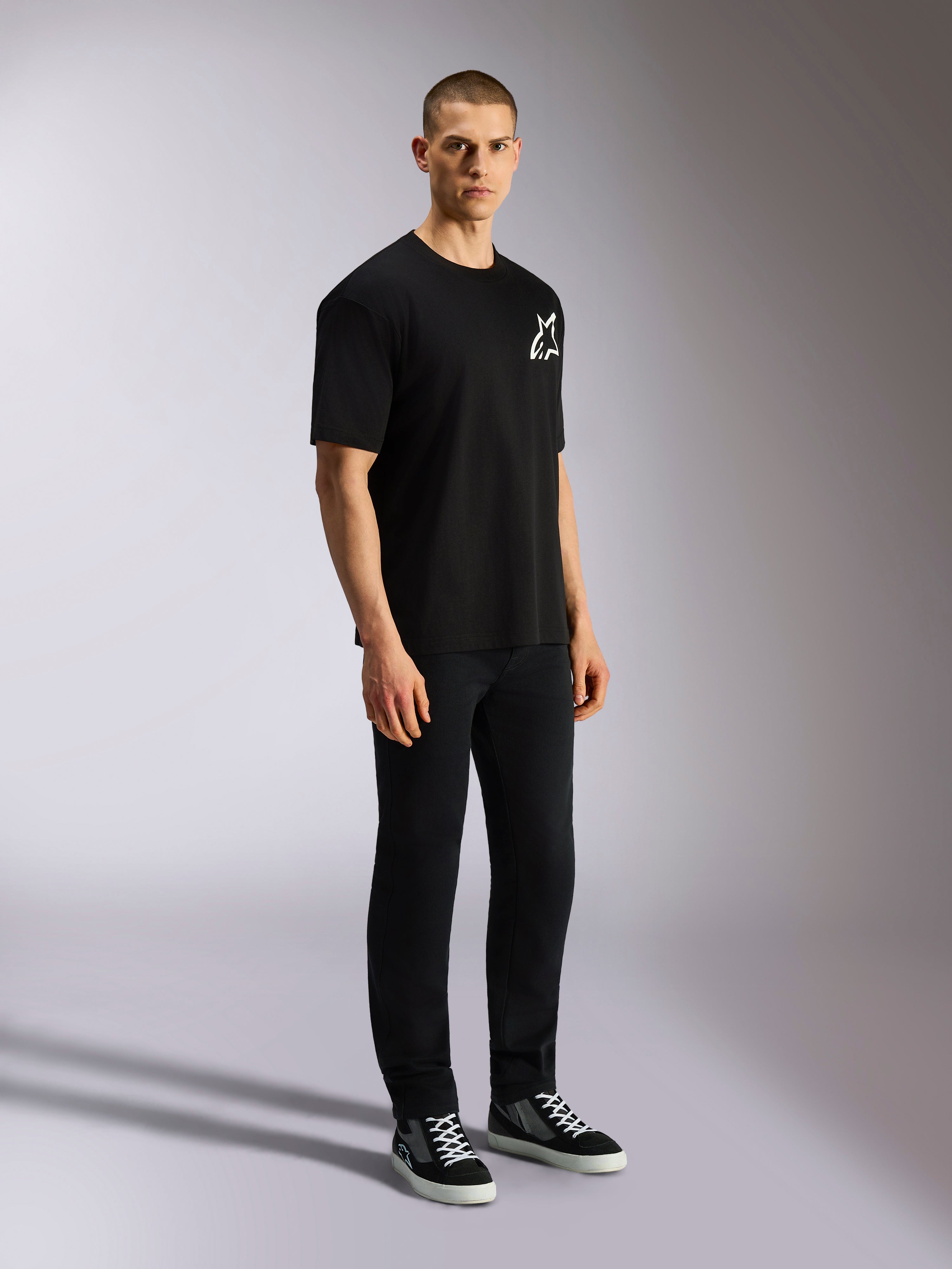 Alpinestars One Oversized CSF Tee, Kurzarm-T-Shirt, Schwarz, weißes Astars-Logo auf der Brust, Oversized-Passform, getragen von einem männlichen Model mit schwarzer Hose und Sneakern, lässige vom Motorsport inspirierte Streetwear