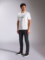 Alpinestars Lanes CSF T-Shirt, weißes Kurzarm-T-Shirt, getragen von einem Model mit schwarzer Slim-Fit-Hose und schwarzen High-Top-Sneakern, blaue und gelbe horizontale Streifen mit Alpinestars-Branding auf der Brust, lässige Motorsport-inspirierte Streetwear