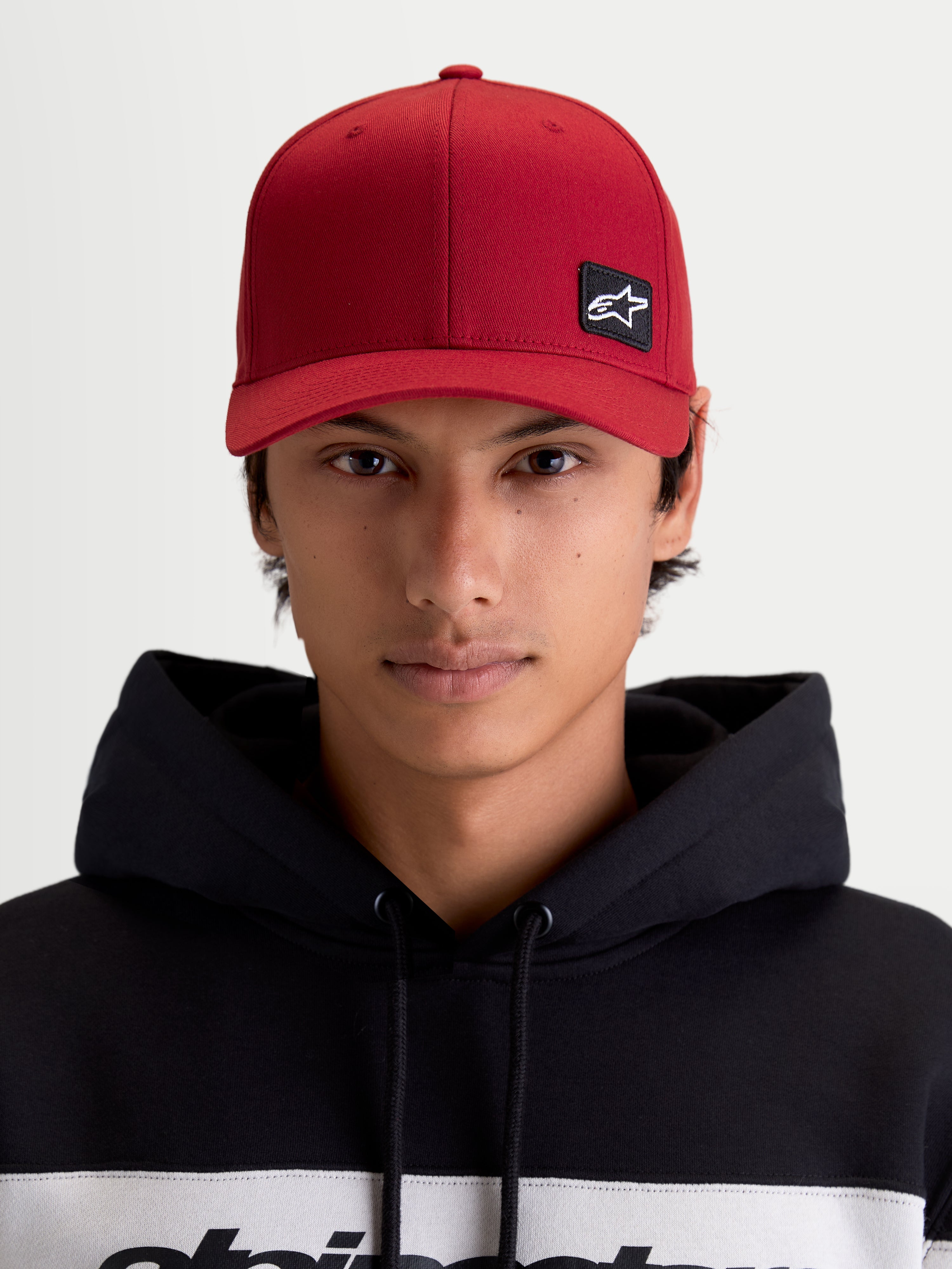 Alpinestars Pivot Kappe, Sportswear Baseballkappe, Unisex, Dunkelrot, Vorderansicht am Modell mit besticktem Astars-Logo-Patch, gebogenem Schirm, strukturierter Krone und strapazierfähiger Twill-Konstruktion.