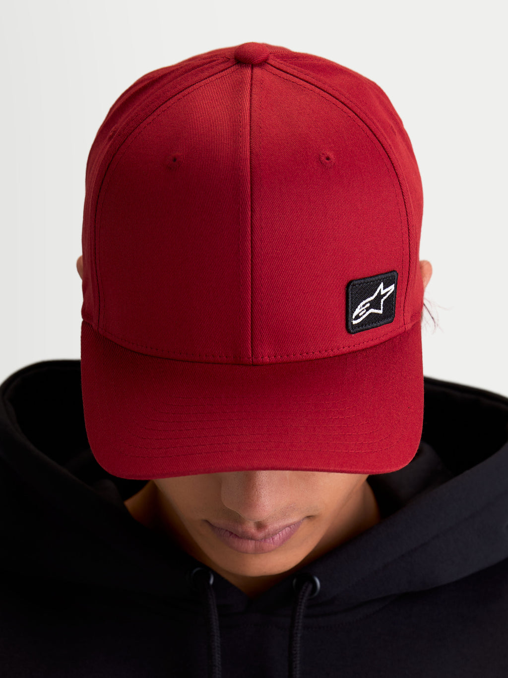 Alpinestars Pivot Kappe, Sportswear Baseball-Cap für den Alltag, Dunkelrot, Unisex, mit gebogenem Schirm, strukturierter Krone und kleinem schwarzen Astars Logo-Stickpatch auf strapazierfähigem Twill-Gewebe, Ansicht am Model.