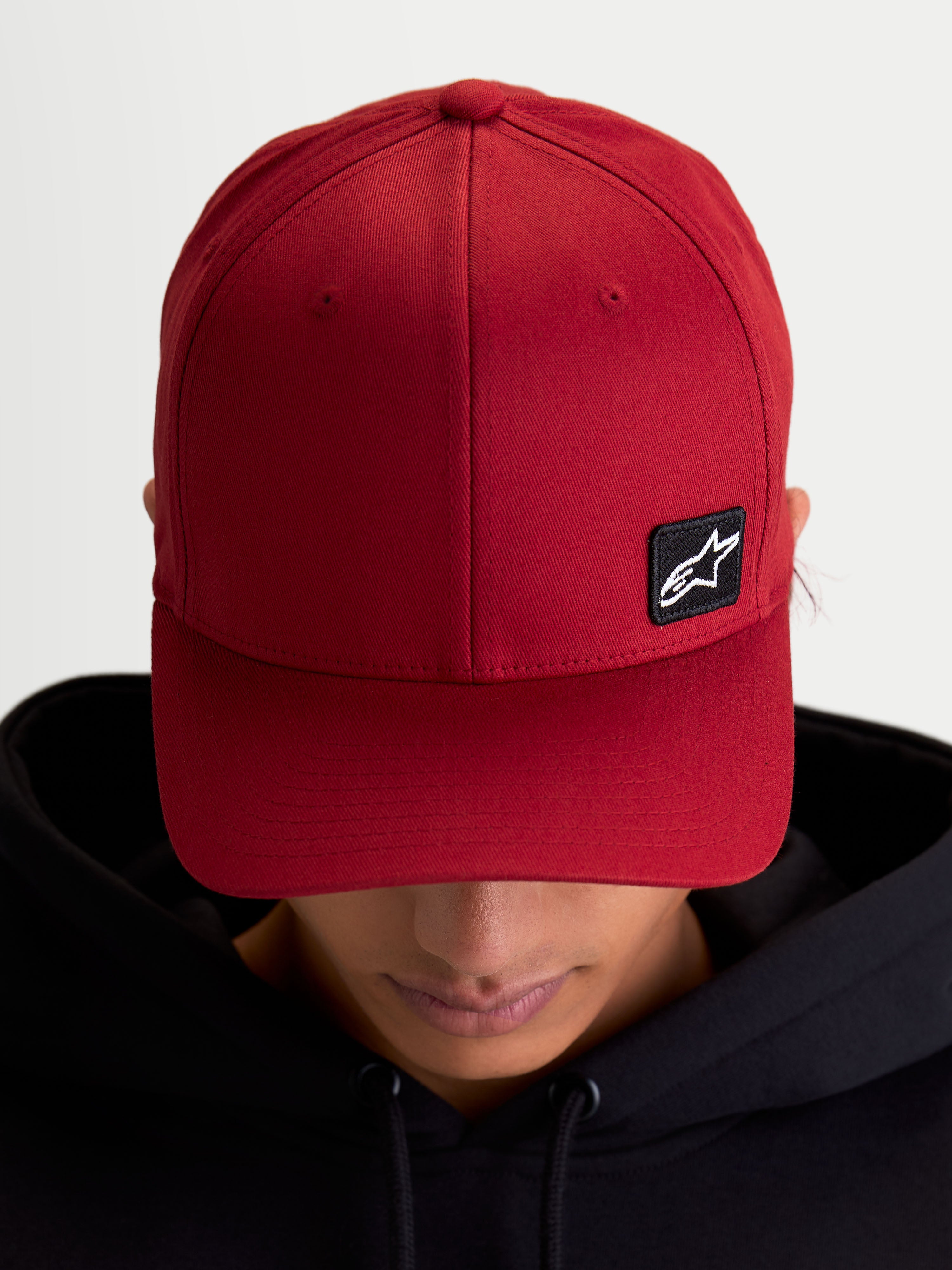 Alpinestars Pivot Kappe, Sportswear Baseball-Cap für den Alltag, Dunkelrot, Unisex, mit gebogenem Schirm, strukturierter Krone und kleinem schwarzen Astars Logo-Stickpatch auf strapazierfähigem Twill-Gewebe, Ansicht am Model.