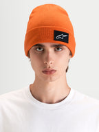 Alpinestars Augment Cuff Mütze, Sportswear-Mütze in Orange mit gewebtem Astars-Logo-Patch, getragen von einem Model mit tiefer Passform