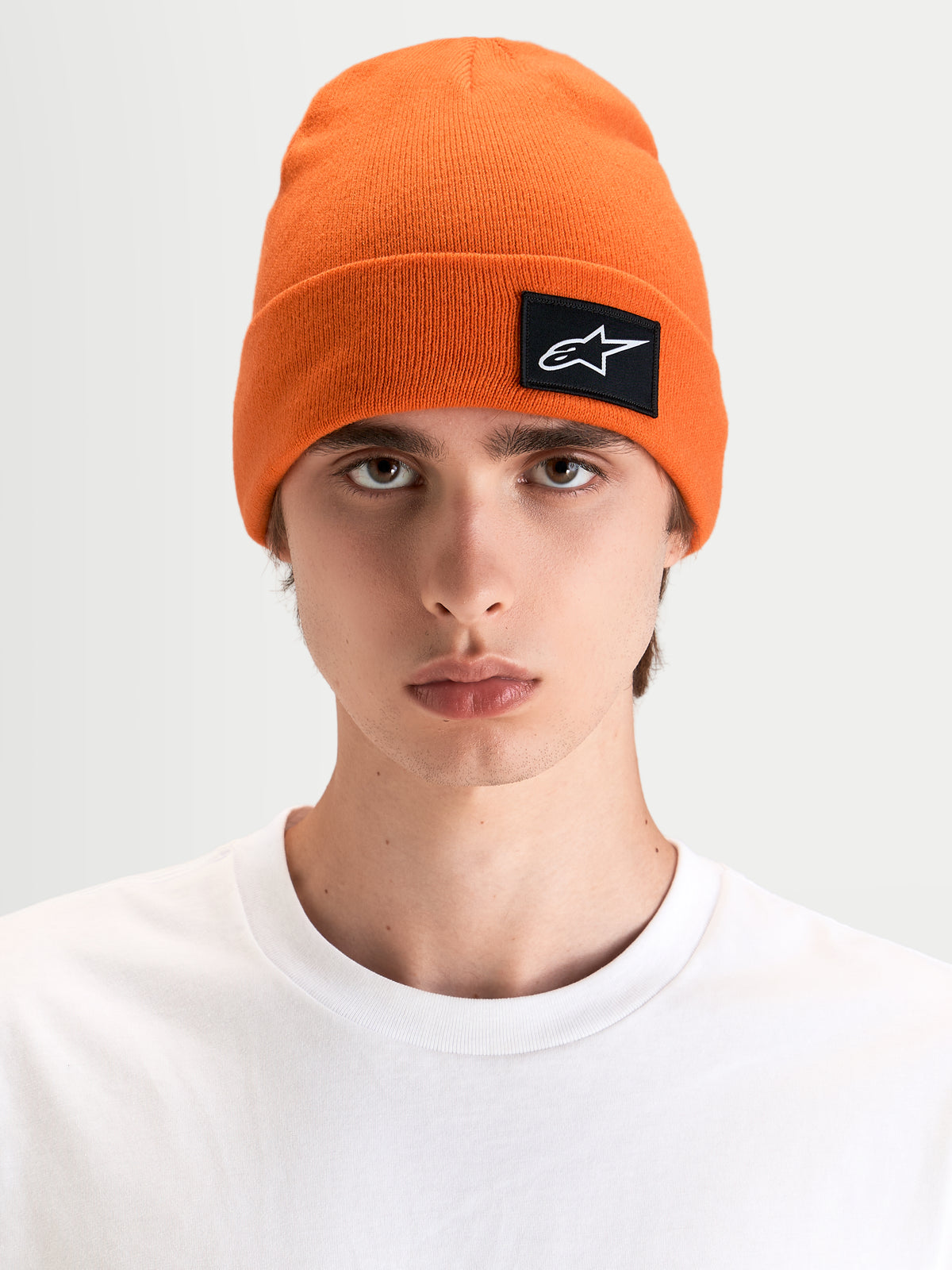 Alpinestars Augment Cuff Mütze, Sportswear-Mütze in Orange mit gewebtem Astars-Logo-Patch, getragen von einem Model mit tiefer Passform