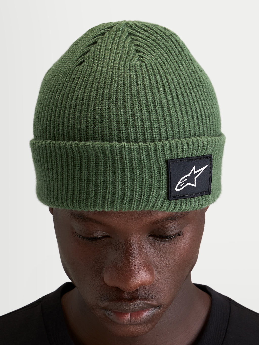 Alpinestars Unload Rib Cuff Mütze, erbsengrüne Strickmütze aus Acryl, geripptes Design mit gewebtem Alpinestars-Logoaufnäher am Umschlag, getragen von einem Model