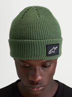 Alpinestars Unload Rib Cuff Mütze, erbsengrüne Strickmütze aus Acryl, geripptes Design mit gewebtem Alpinestars-Logoaufnäher am Umschlag, getragen von einem Model