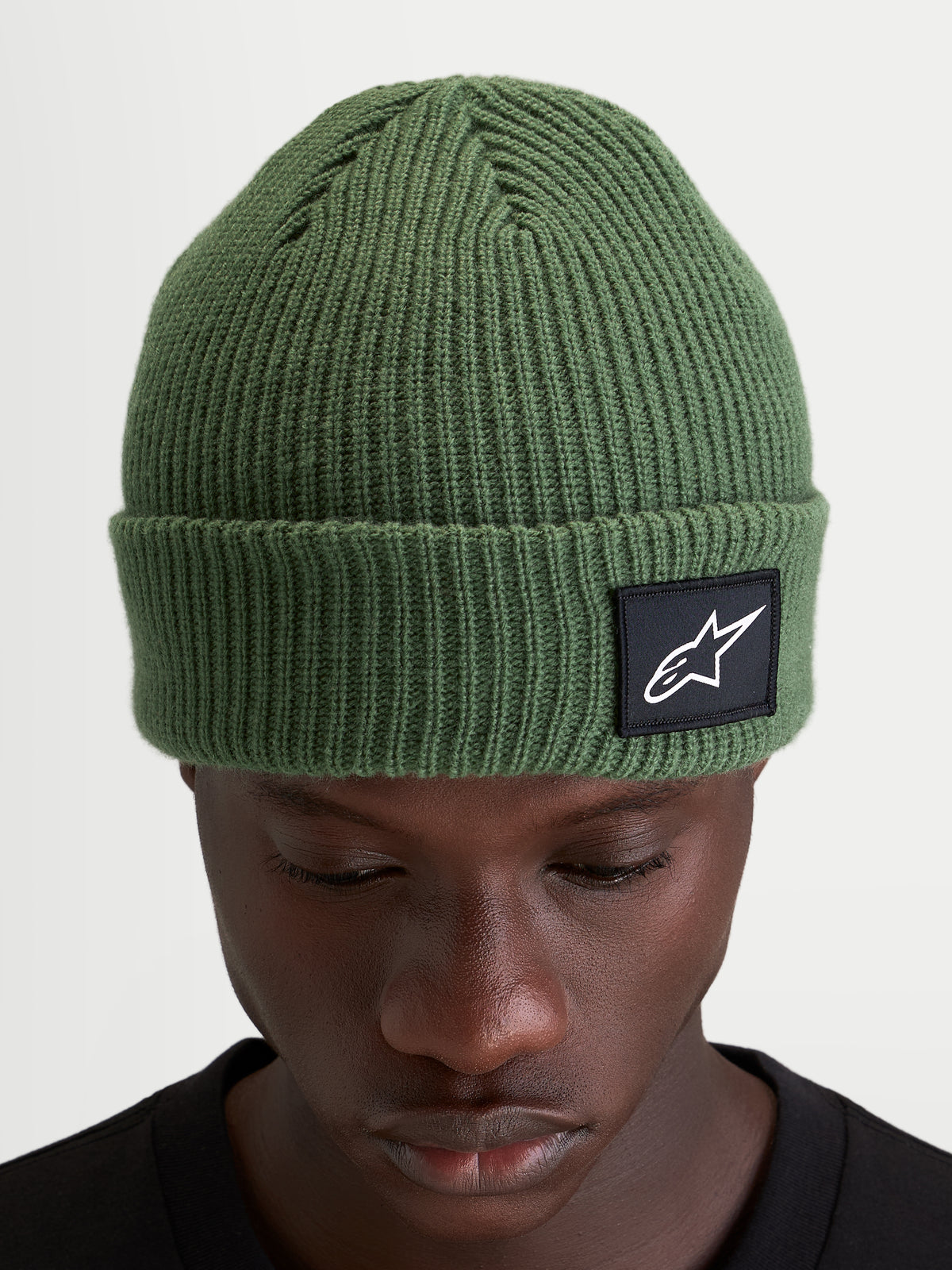 Alpinestars Unload Rib Cuff Mütze, erbsengrüne Strickmütze aus Acryl, geripptes Design mit gewebtem Alpinestars-Logoaufnäher am Umschlag, getragen von einem Model