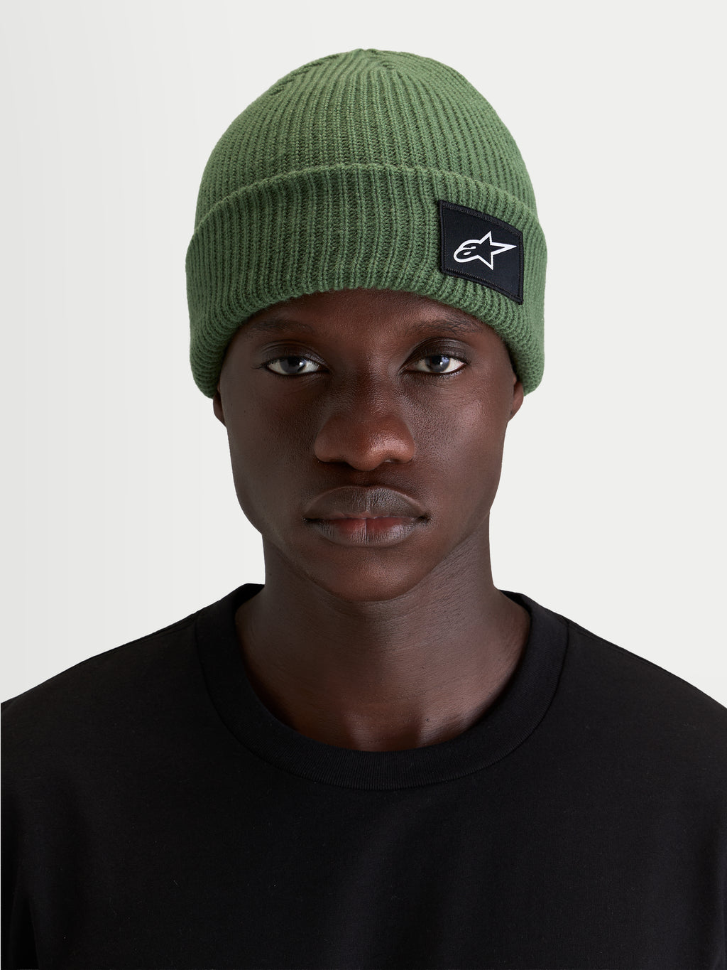Alpinestars Unload Rib Cuff Mütze, grüne Sportswear-Mütze im Strickdesign mit flacher Passform und gewebtem SAstars-Aufnäher, getragen von einem Model