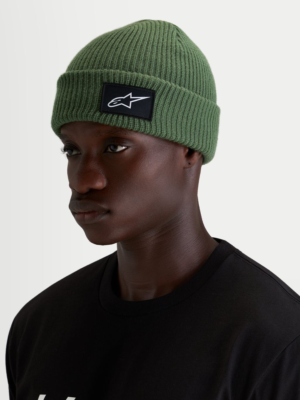 Alpinestars Unload Rib Cuff Mütze, grüne Casual-Wintermütze, getragen von einem Model, mit Rippstrick-Konstruktion und schwarz-weißem SAstars-Vorderaufnäher