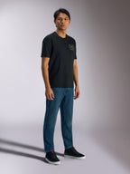 Alpinestars Order CSF Tee, Short Sleeve T-Shirt, Black, Featuring Green Helmet and Palm Tree Logos on Chest, Casual Motorsport Streetwear, Worn with Blue Jeans and Black Sneakers
