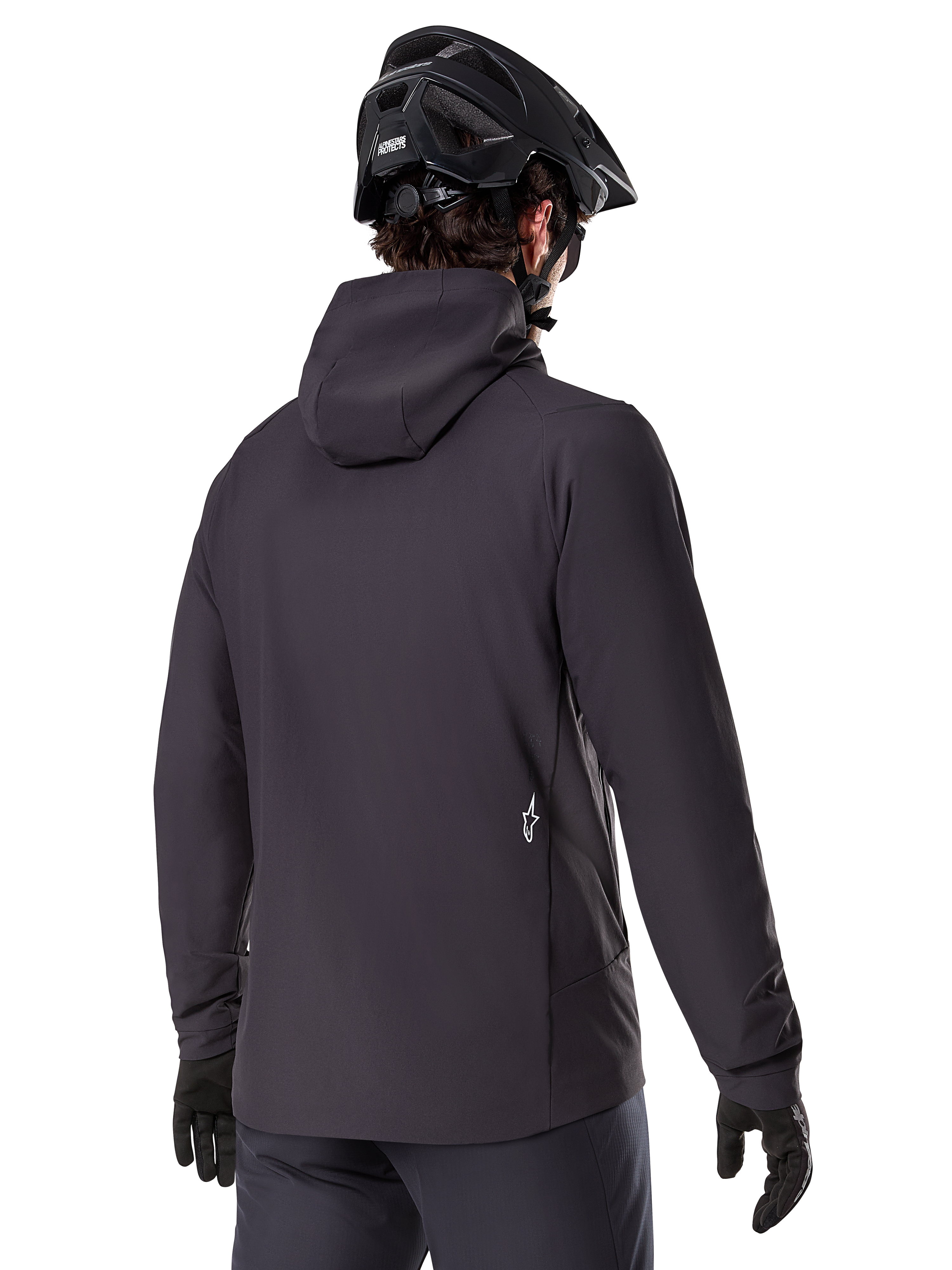 Alpinestars A-Dura Thermojacke, Schwarz, Rückansicht, getragen mit einem schwarzen Mountainbike-Helm und Handschuhen, kleines weißes Astars-Logo auf dem unteren Rücken, leichte isolierte Radjacke