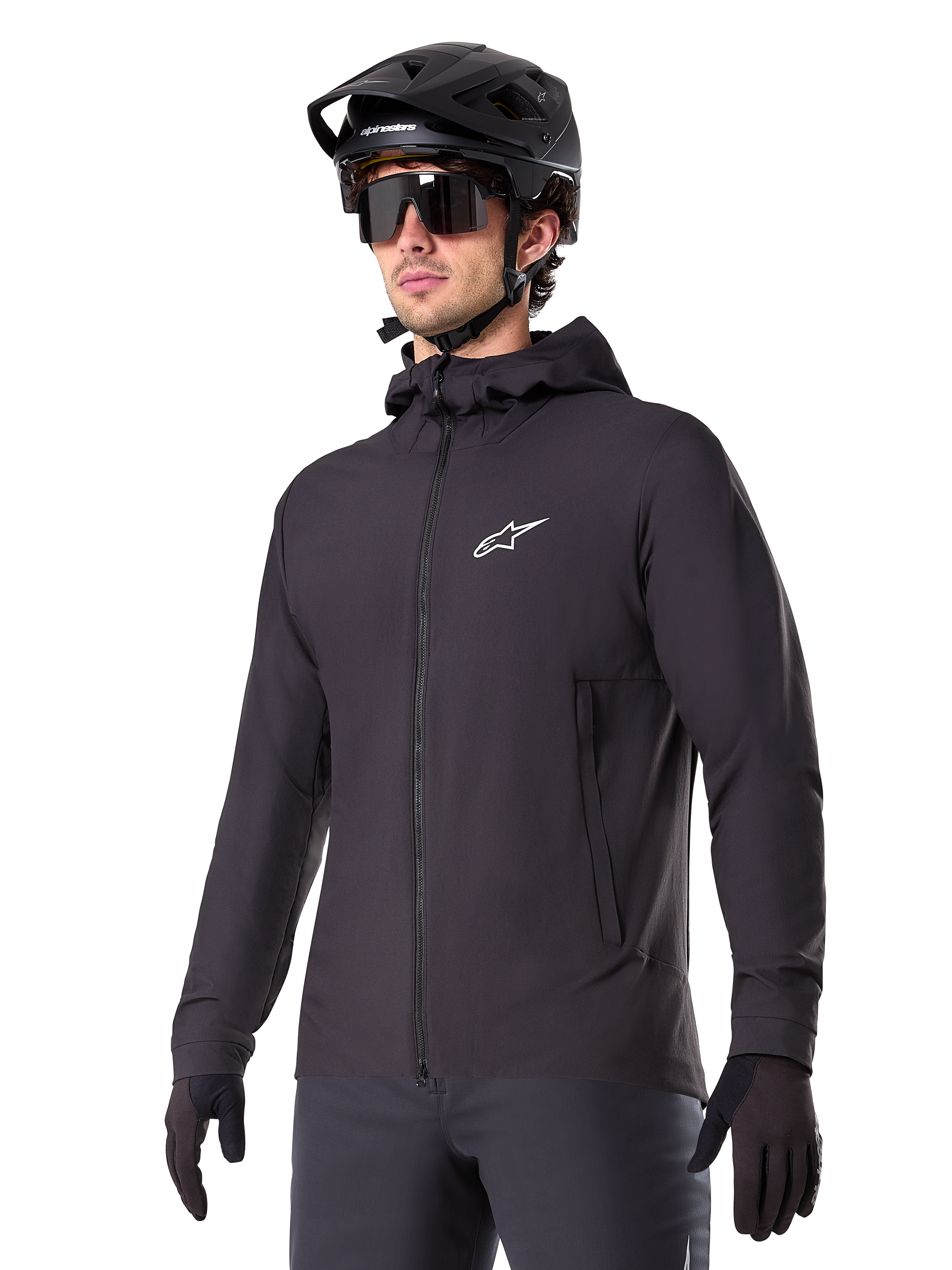 Alpinestars A-Dura Thermal Jacket, schwarze Fahrradjacke, Design mit Kapuze und Frontreißverschluss, weißes Stern-Logo auf der Brust, getragen mit schwarzem Mountainbike-Helm und Handschuhen, sportliche Funktionsbekleidung für Trailfahrten bei kaltem Wetter
