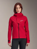 Alpinestars Stella A-Dura Elite Wasserdichte Jacke, Damen-Mountainbike-Jacke, Rot Fluo, Kapuzendesign mit asymmetrischer Frontklappe, weißes Alpinestars-Logo auf der Brust, verstellbare schwarze Ärmelbündchen, getragen von einem weiblichen Model mit schwarzer Hose