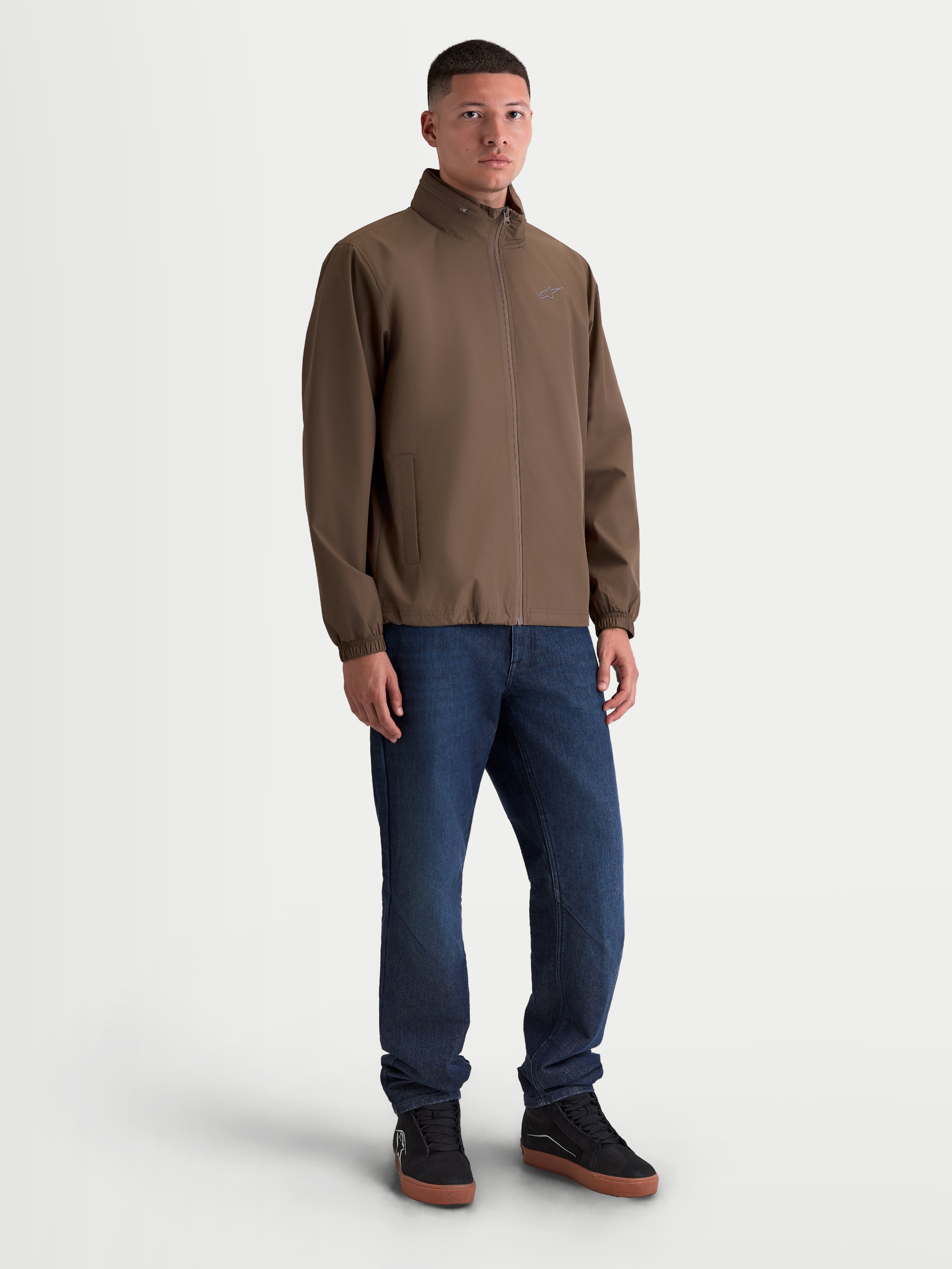Alpinestars Overhaul Racer Jacke, leichte Sportswear-Jacke für Herren in Walnussbraun. Die Jacke zeigt eine Motorsport-Silhouette mit dezentem Astars-Logo auf der Brust, eine verstaubare Kapuze im Kragen und Mesh-Futter für den Alltag.