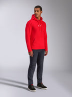Alpinestars Frontal Hoodie, Rot, männliches Model trägt Fleece-Kapuzenpullover mit weißem A-Star-Brustlogo, Kängurutasche, Kapuze mit Kordelzug, kombiniert mit dunklen Denim-Jeans, lässige vom Motorsport inspirierte Streetwear