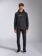 Alpinestars Frontal Hoodie, schwarzer Fleece-Kapuzenpullover, weißes Alpinestars-Logo auf Brust und Ärmel, Kängurutasche, Kapuze mit Kordelzug, kombiniert mit schwarzer Hose, lässiges vom Motorsport inspiriertes Design