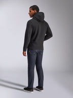 Alpinestars Blaze V3 Hoodie, Rückansicht eines Mannes im schwarzen Kapuzenpullover, kombiniert mit dunkler Jeans und schwarzen Sneakern, lässige Motorsport-inspirierte Streetwear