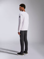 Alpinestars Bettern Crew, weißes Crewneck-Sweatshirt, Rück- und Seitenansicht, schwarzes kreisförmiges Logo am Ärmel, getragen mit dunkelgrauer Hose und schwarzen Sneakern, lässige Motorsport-Lifestyle-Streetwear