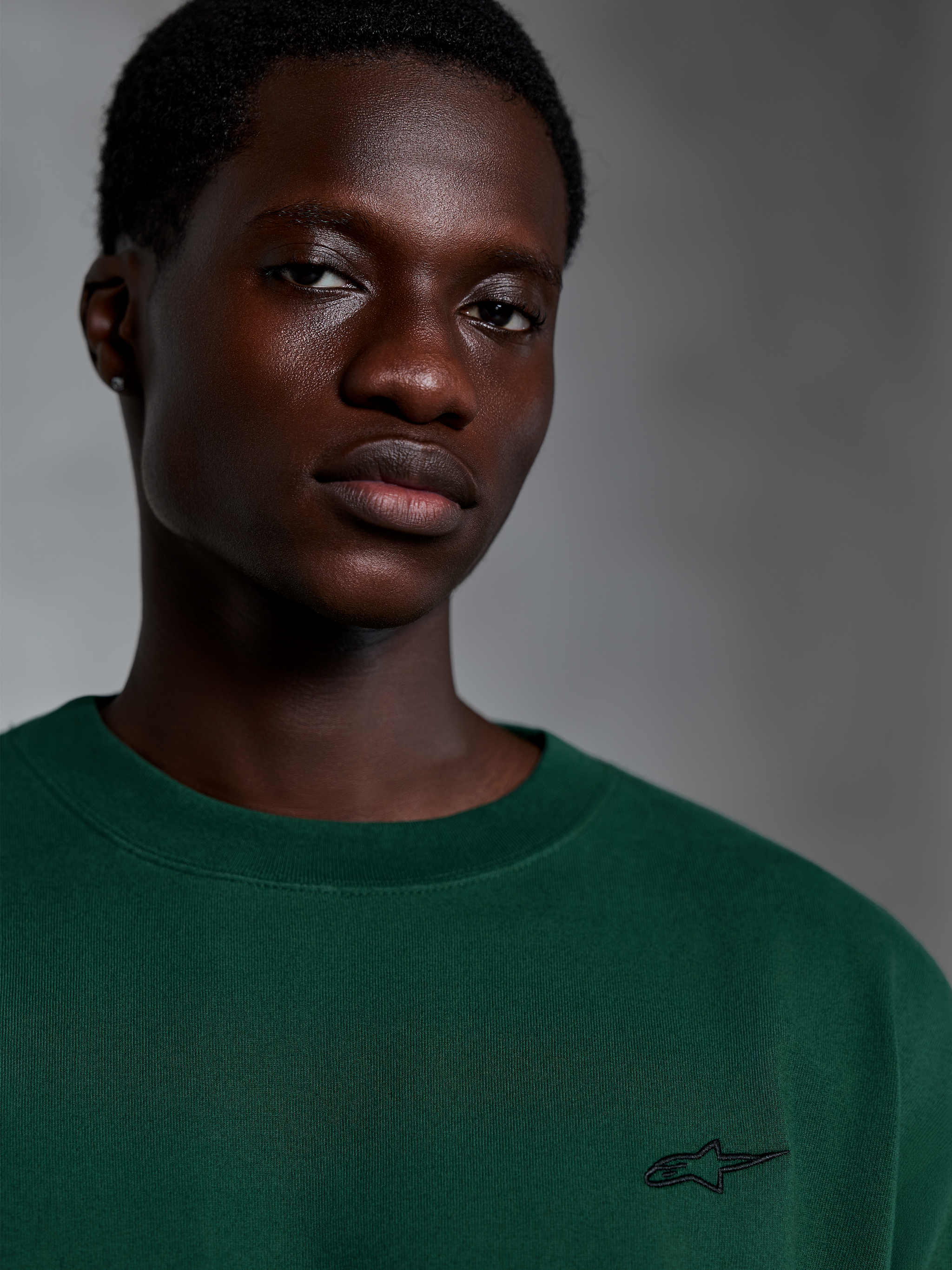 Alpinestars Essentials Ageless SS Tee, Pine Green Short Sleeve T-Shirt, Close-up of model wearing green organic cotton tee with small embroidered logo, casual streetwear design