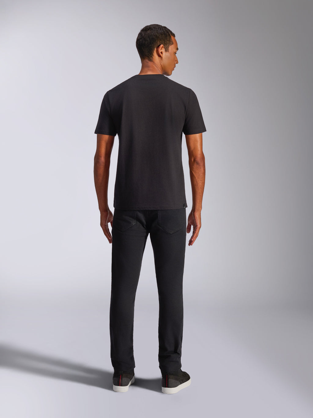 Alpinestars Shaded CSF Tee, Kurzarm-T-Shirt, Schwarz, Rückansicht an einem Model in schwarzer Hose, lässige, vom Motorsport inspirierte Streetwear