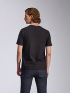 Alpinestars Global CSF Tee, Kurzarm-T-Shirt, Schwarz, Rückansicht getragen von einem Model, kombiniert mit dunkelblauen Jeans, lässige Motorsport-Streetwear