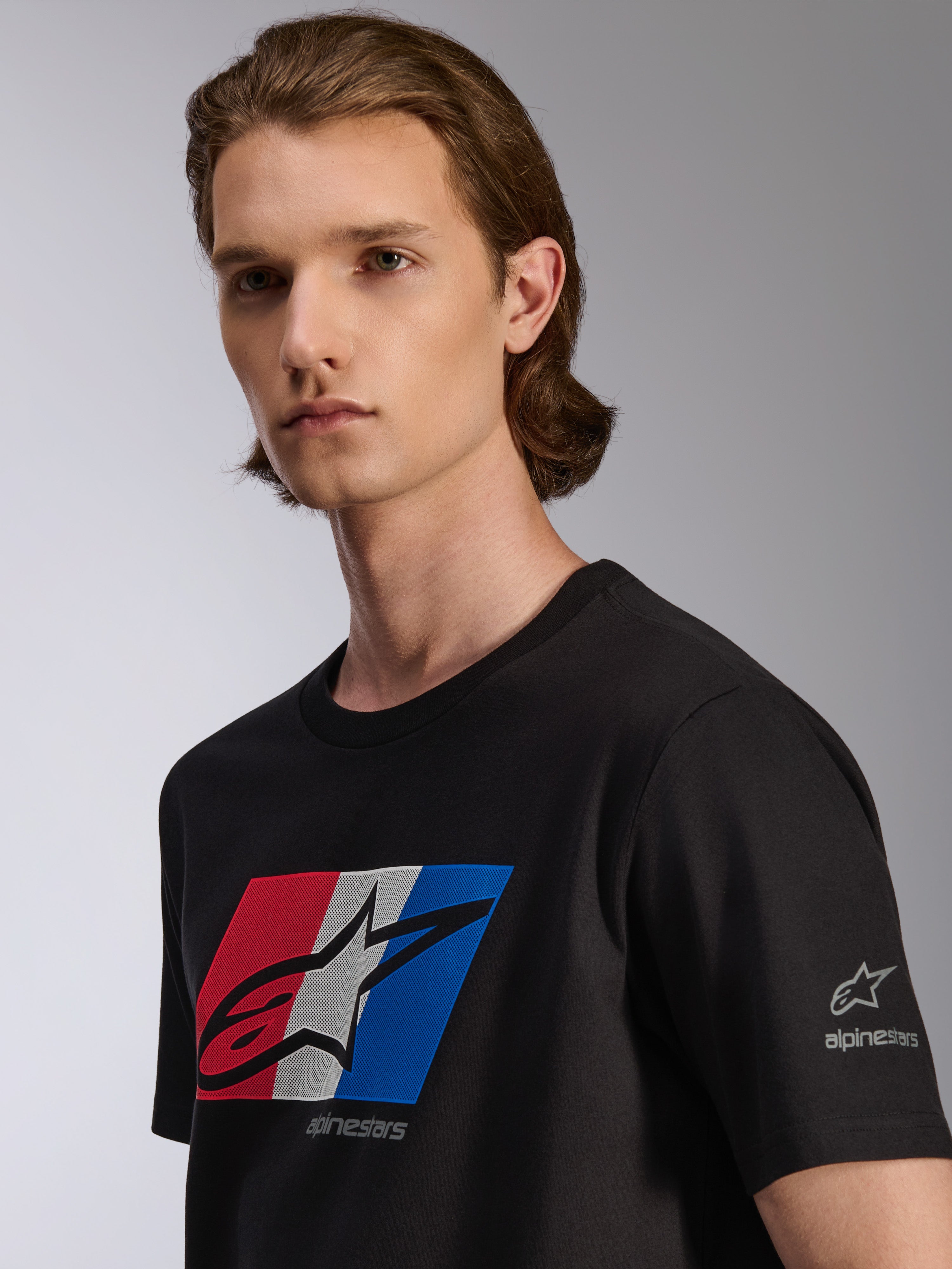 Alpinestars Global CSF T-Shirt, Kurzarm-T-Shirt, Schwarz, Grafik in Rot, Weiß und Blau mit schwarzem Schatten-Logo, Detailansicht am Model, lässige Motorsport-Streetwear