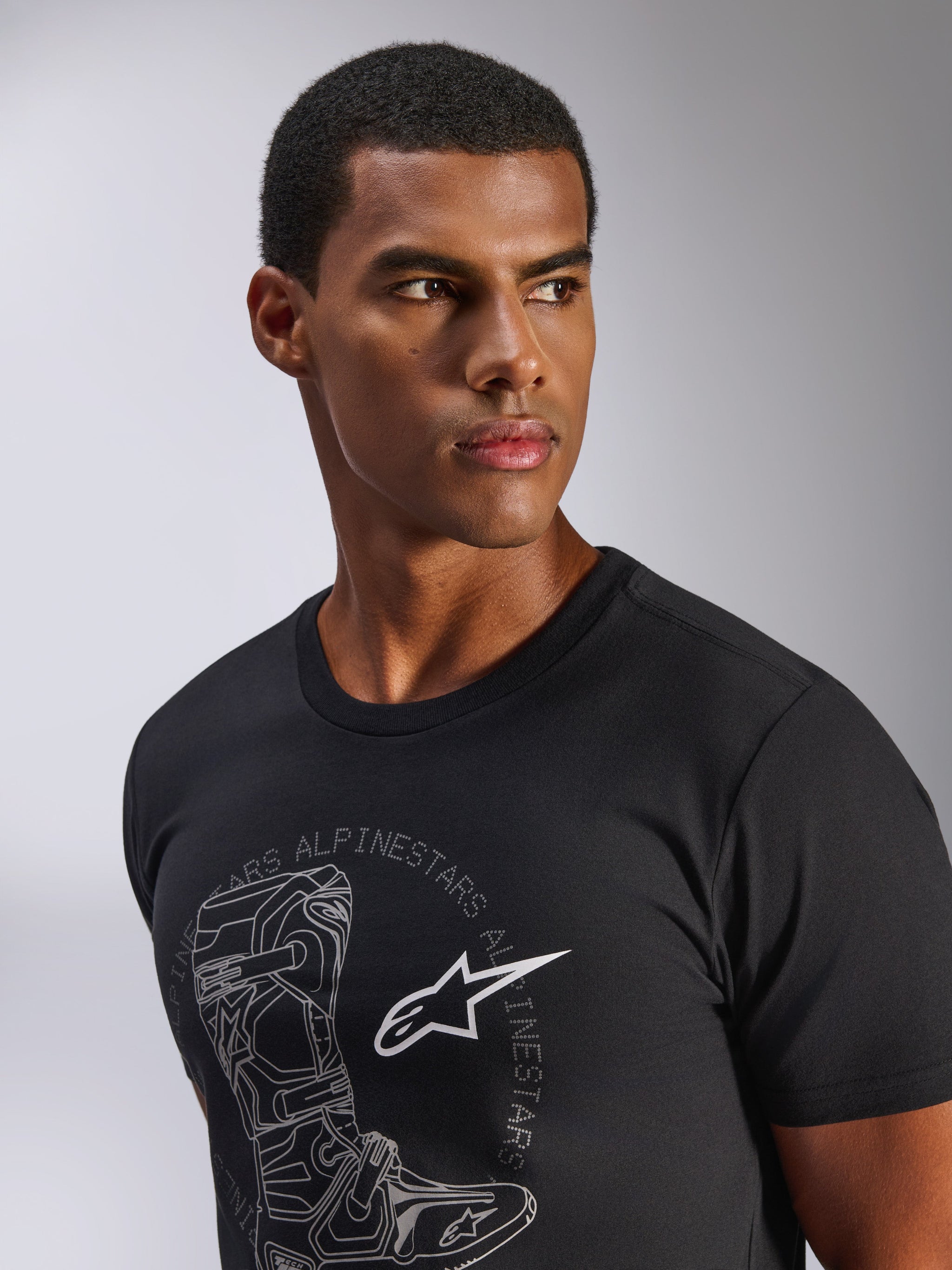 Alpinestars Tech Boot CSF Tee, Kurzarm-T-Shirt, Schwarz, graue Tech Boot Grafik mit weißem Astars Logo, getragen von einem männlichen Model, lässige Motorsport-Streetwear