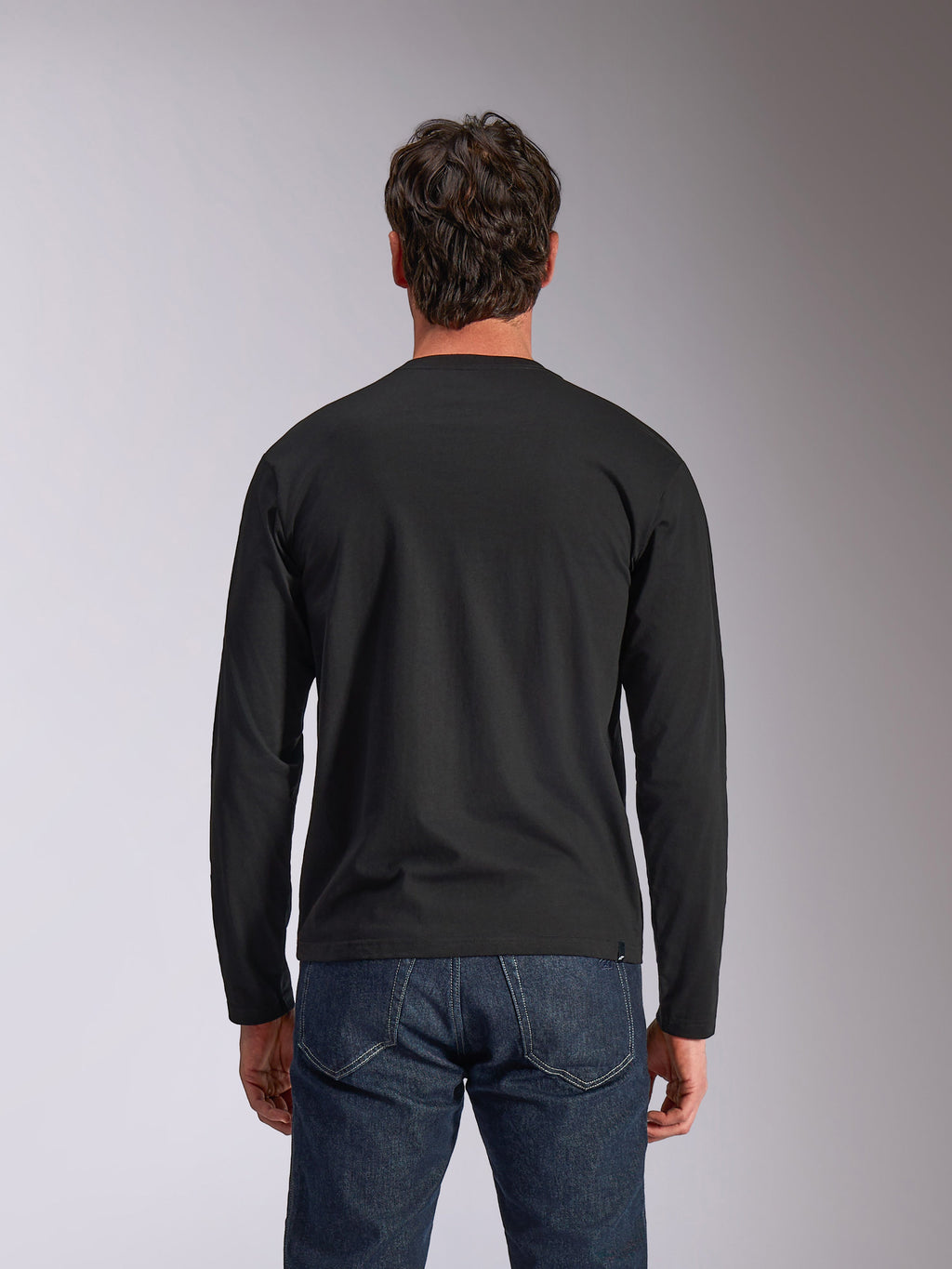 Alpinestars Trackside CSF Tee, Langarmshirt, Schwarz, Rückansicht, getragen mit dunkelblauen Denim-Jeans, lässige Motorsport-inspirierte Streetwear