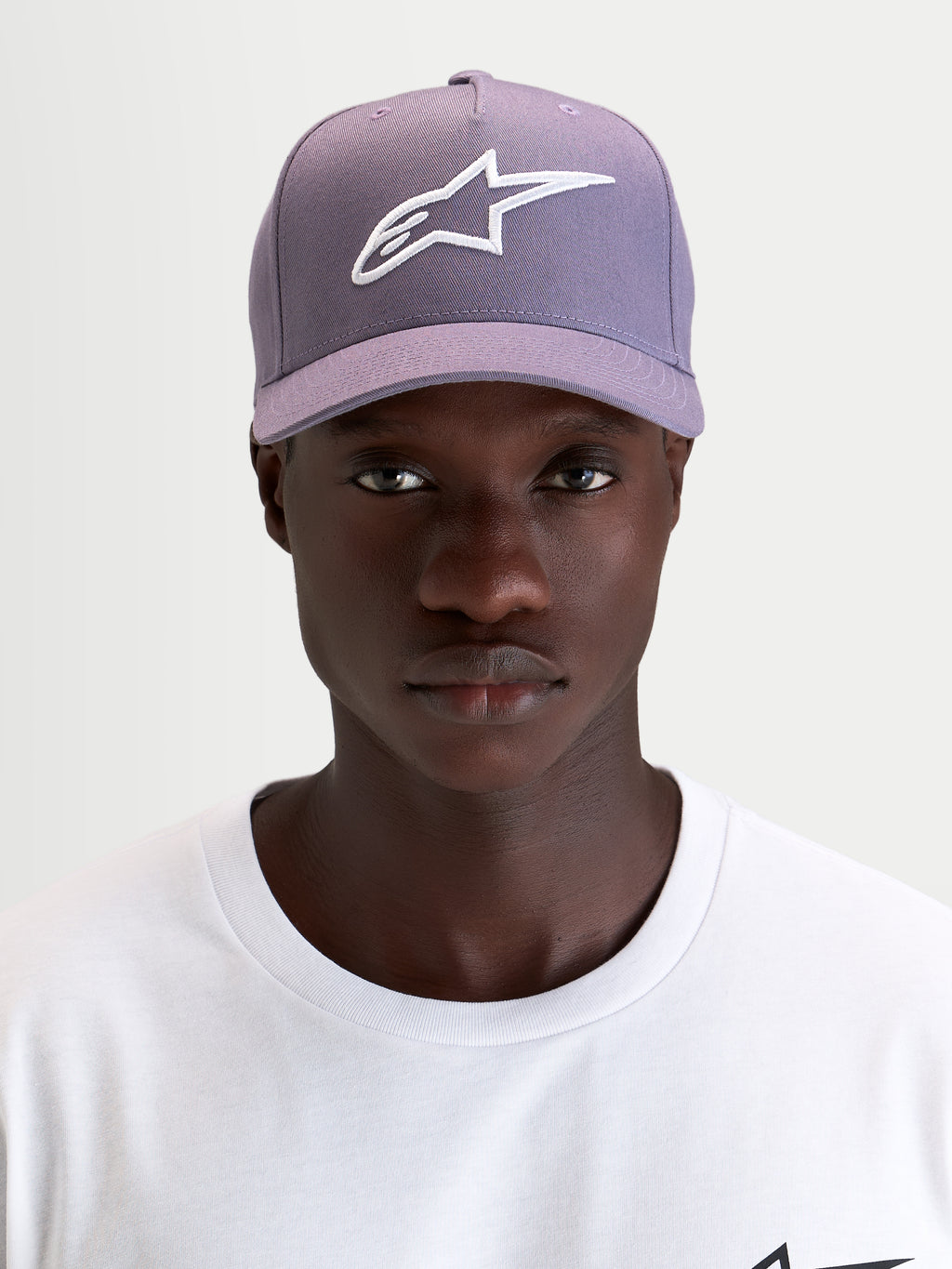 Alpinestars Ageless Snapback Kappe, Sportswear-Cap mit gebogenem Schirm in Lila und Weiß, getragen von einem Model mit strukturierter Twill-Konstruktion und gesticktem 3D-Astars-Logo auf der Vorderseite