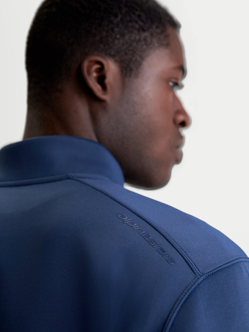 Alpinestars Apera Half-Zip-Sweatshirt, Sportswear-Pullover in Blau, Nahaufnahme der Rückansicht am Modell mit tonalem HD-Alpinestars-Logodruck auf der Schulter und hochwertigem Tri-Blend-Doppelgewebe-Fleece.