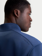 Alpinestars Apera Half-Zip-Sweatshirt, Sportswear-Pullover in Blau, Nahaufnahme der Rückansicht am Modell mit tonalem HD-Alpinestars-Logodruck auf der Schulter und hochwertigem Tri-Blend-Doppelgewebe-Fleece.