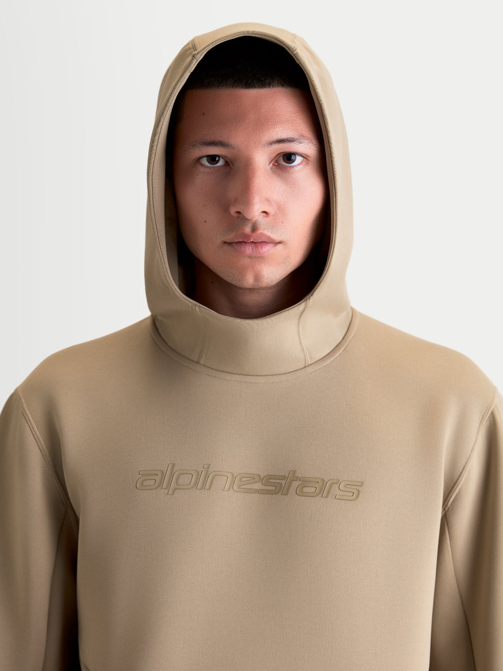 Alpinestars Datrix Hoodie, Sportswear-Kapuzenpullover, Braun, Frontale Nahaufnahme am Model mit aufgesetzter Kapuze, Tonales Alpinestars-Branding auf der Brust, Premium Tri-Blend-Fleece.